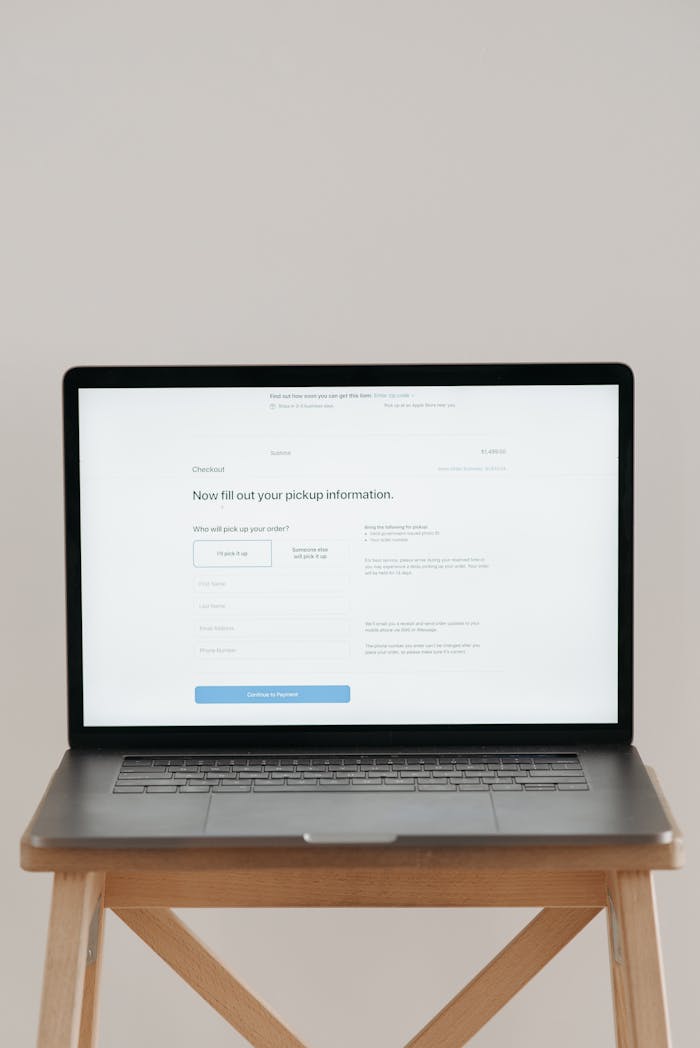 Homepage Modern laptop displaying a checkout form against a minimalist beige backdrop.